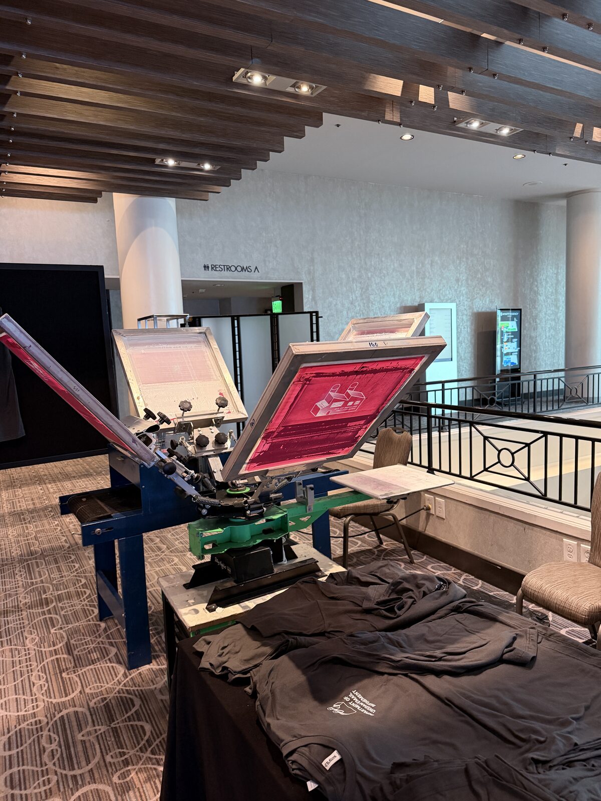 A multi-color press station set up and running at a live event with staff printing custom apparel